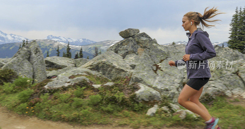 女性trail runner通过高山草甸跟随小路